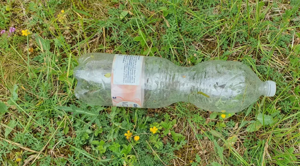 Plastová lahev clever leží na louce