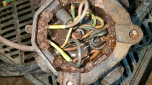 Elektroinstalační krabice dovnitř vedou 2 kabely, zcela zrezivělé šrouby a můstky, uvnitř voda způsobující zkrat